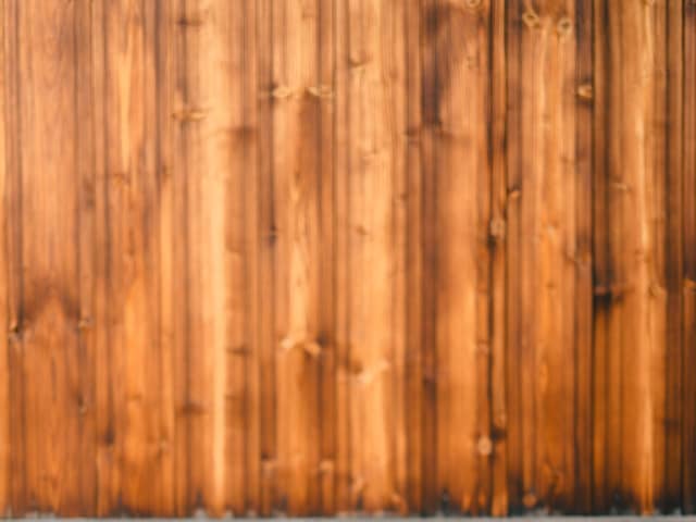 Freshly milled cedar pickets beside a weathered grey fence panel.
