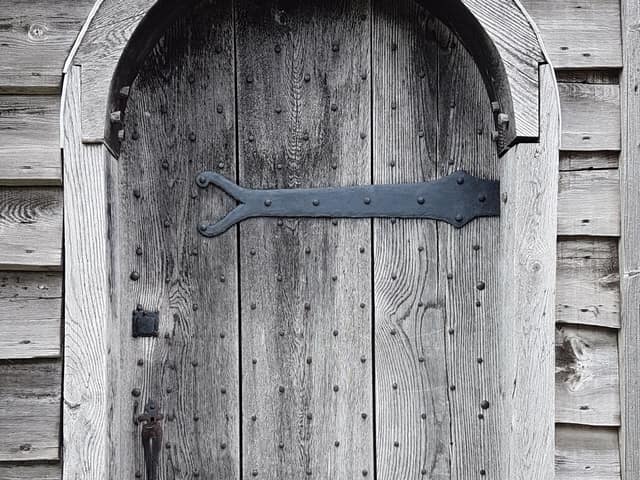 A heavy strap hinge and its fixings on a timber gate.