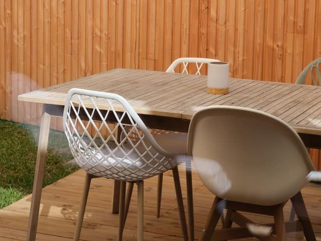 A horizontal cedar privacy fence enclosing a patio with a table and chairs.